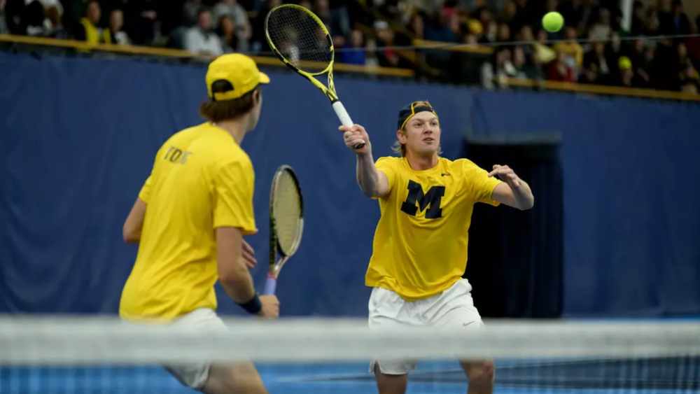 U-M Men's Tennis player returning a shot in a doubles match