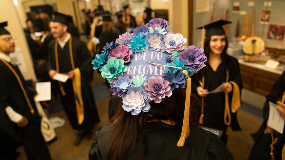 Student at Commencement with their cap decorated with flowers and text that reads 