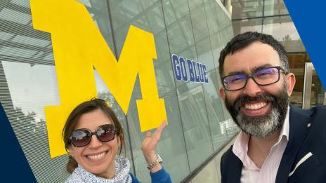 Miguel smiling in front of the block M and a go blue mural at the Ross School of Business