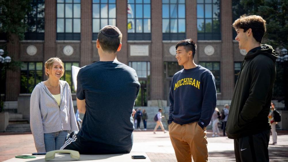 Four students talking together on the University Diag, with one visibly wearing a kippah.