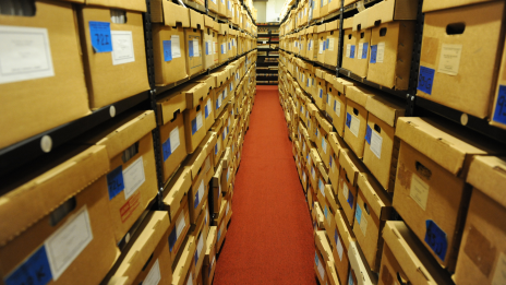 rows of boxes on shelves along an aisle with red carpet